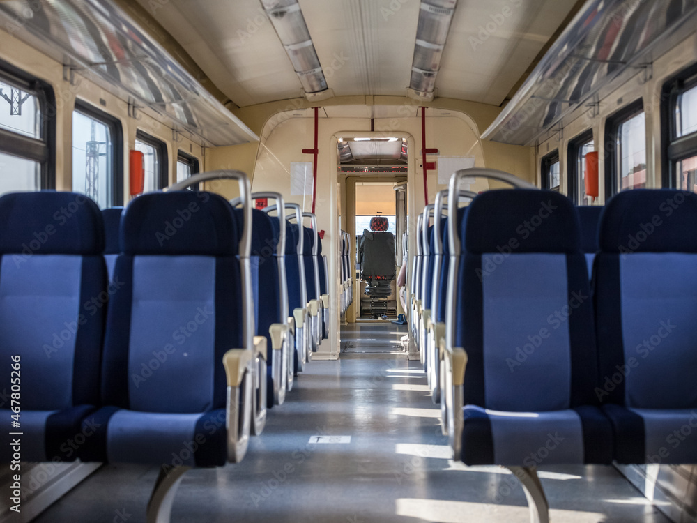 Row of Empty seats in a modern regional train with a driver cab in background, European style, on a travel in a countryside with a speed blur effect seen from the window...