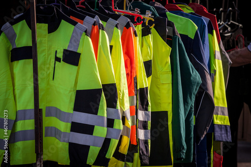 Selective blur on high visibility safety coats and jackets, personal protective equipments, for sale outside, fluorescent colors. These coats are made to be visible on workplace in any condition. ..
