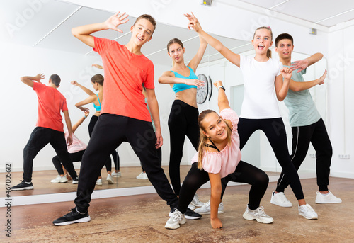 Group portrait of fine teenagers with young female choreographer in modern dance studio