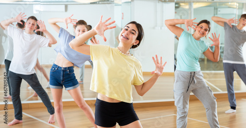 Positive teen girl exercising in group with friends during dance class