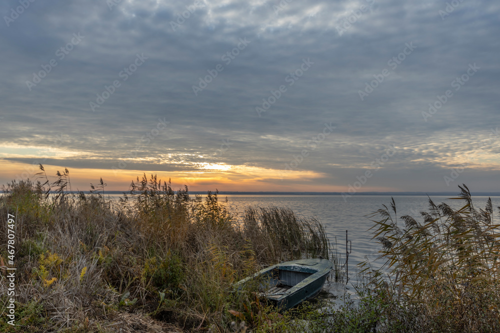 Obraz premium Colorful sunrise on the shores of Lake Nero. Autumn landscape with a lake in the early morning. A bright streak of light on the horizon, dawn.