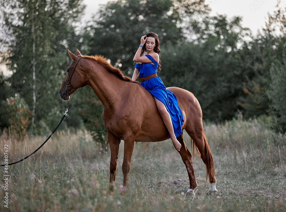 Beautiful long-haired girl in a blue dress riding a red horse Beautiful long-haired girl in a blue dress riding a red horse