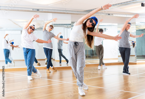 Happy smiling teenagers practicing vigorous hip hop movements in dance class