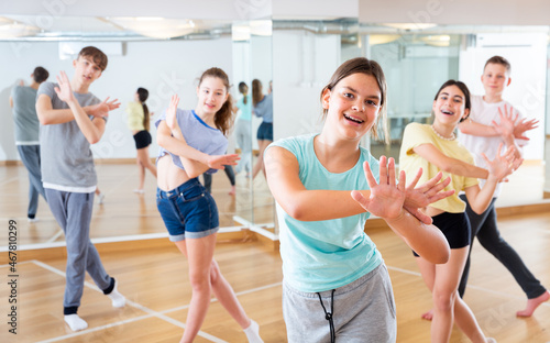 Positive teen girl exercising in group with friends during dance class