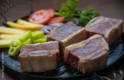 BEEF CUT INTO PIECES, WITH VEGETABLES SUCH AS TOMATO, ONION, PARSLEY, PEPPERS AND POTATOES, ON GRILL, READY TO BRING TO THE FIRE