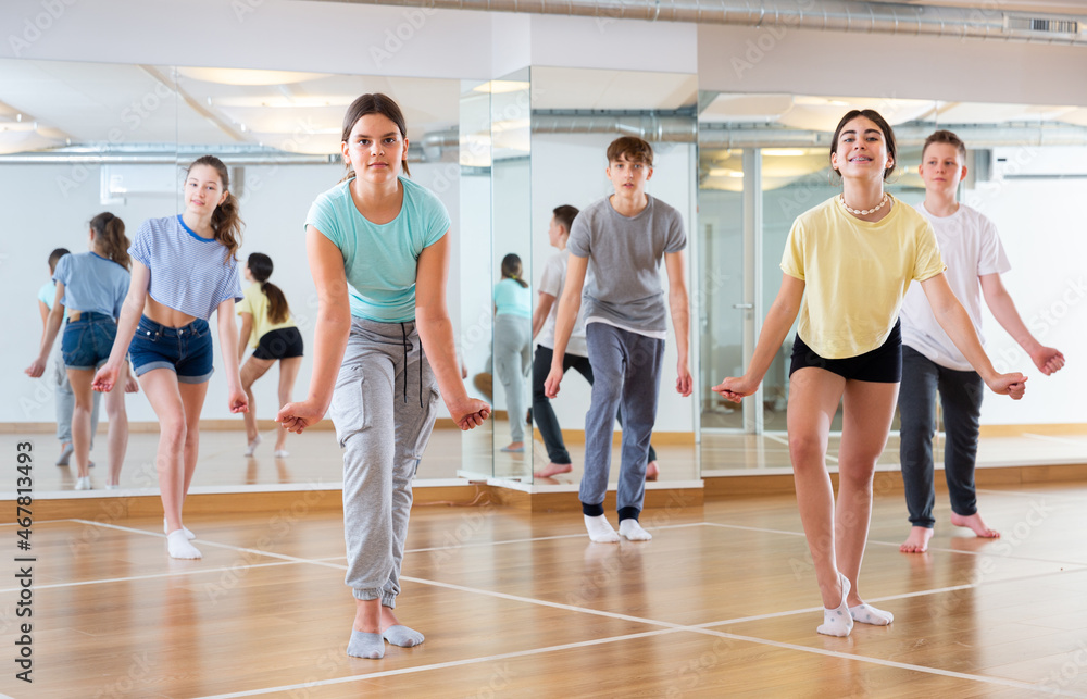 Positive smiling slim teenagers dancing hip hop in dance class
