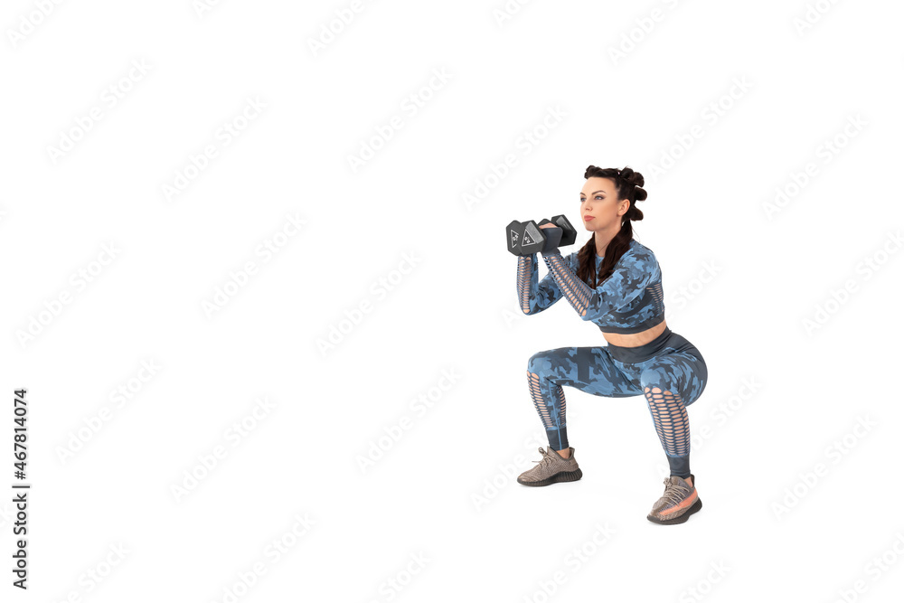 Beautiful sporty woman in a blue camouflage tracksuit is engaged in fitness. Does an exercise in a rack with dumbbells on an isolated white background. Sports and healthy lifestyle Beautiful sporty woman in a blue camouflage tracksuit is engaged in fitness. Does an exercise in a rack with dumbbells on an isolated white background. Sports and healthy lifestyle