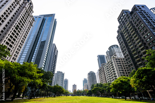 Low-angle view of green park space and modern buildings on both sides in downtown Taichung  Taiwan. here is near the National Taichung Theater.