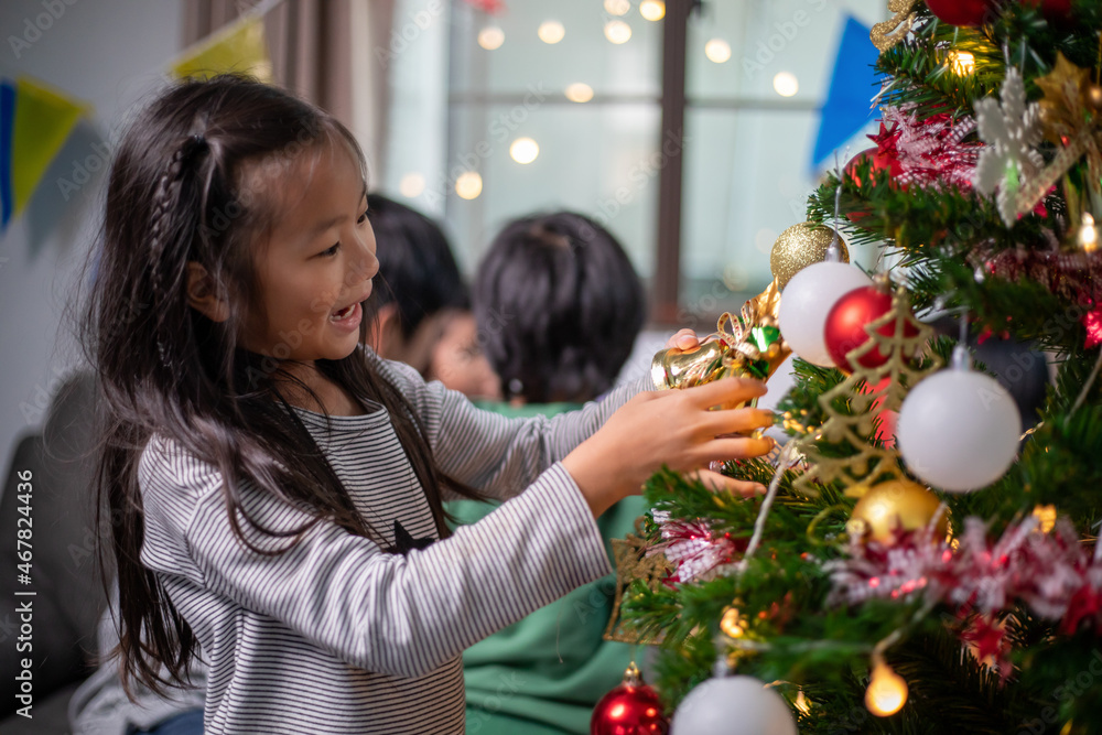 Asian little girl is decorating Christmas tree and enjoying Christmas time Asian little girl is decorating Christmas tree and enjoying Christmas time