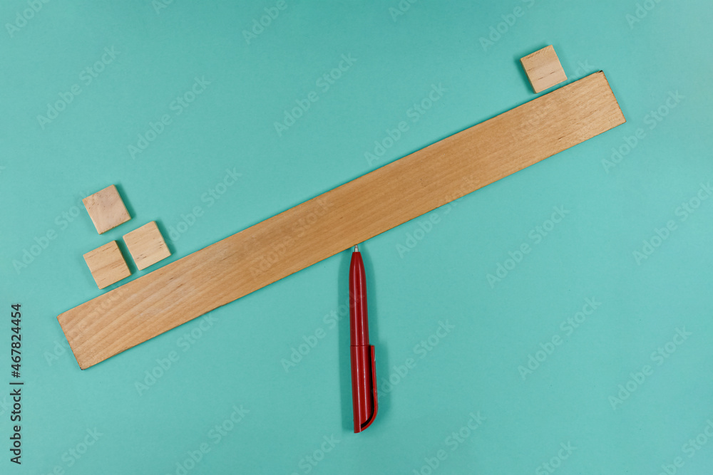 Wooden cubes on the scale from the ruler, that are not balanced, on blue paper background