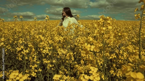 Happy beautiful young woman in rapeseed flowers field. Woman freedom. Woman power. Women rights.
