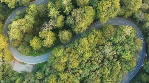 Travel time in the fall season, drone footage as top down shot at a double curve under sunshine with a driving car photo