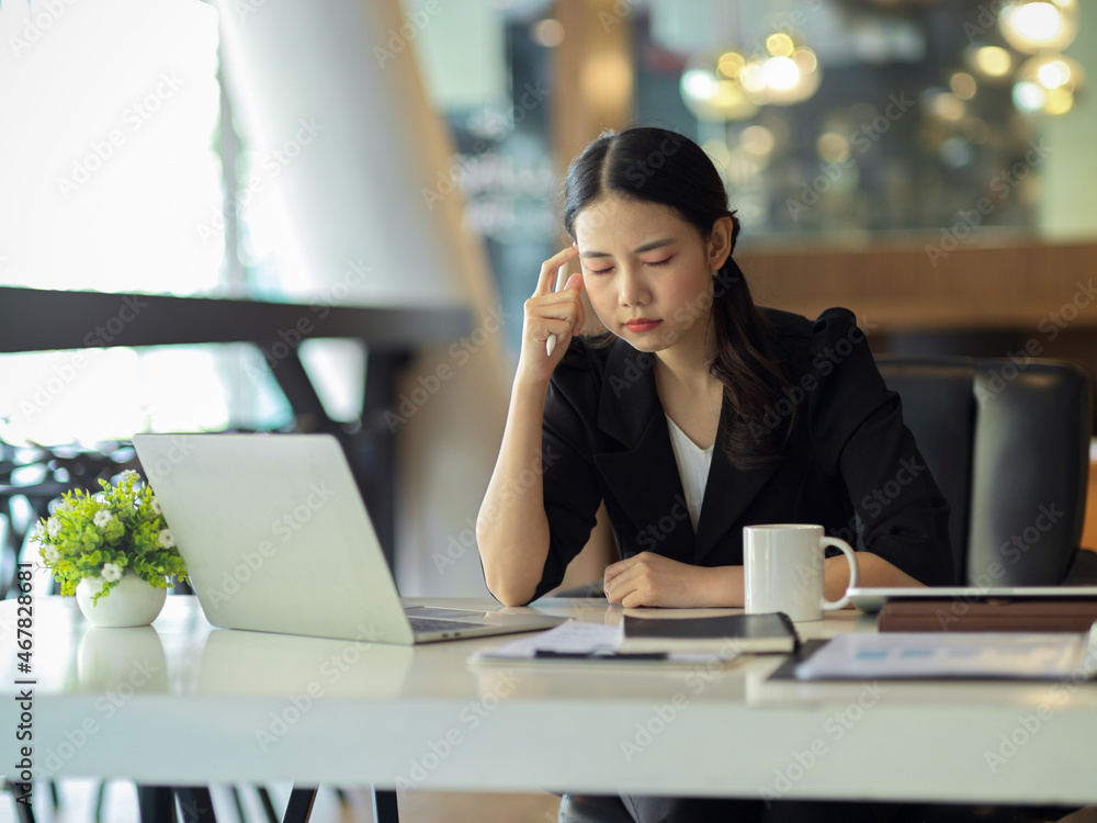 Fototapeta premium A businesswoman gets a headache while trying to solve problems at work