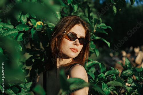 pretty woman wearing sunglasses green leaves posing summer