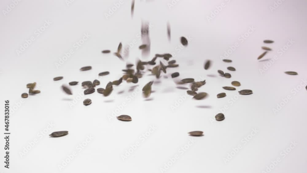 Roasted And Shelled Pumpkin Seeds Falling And Scattering On Clean Surface Isolated In White Background. close up Roasted And Shelled Pumpkin Seeds Falling And Scattering On Clean Surface Isolated In White Background. close up