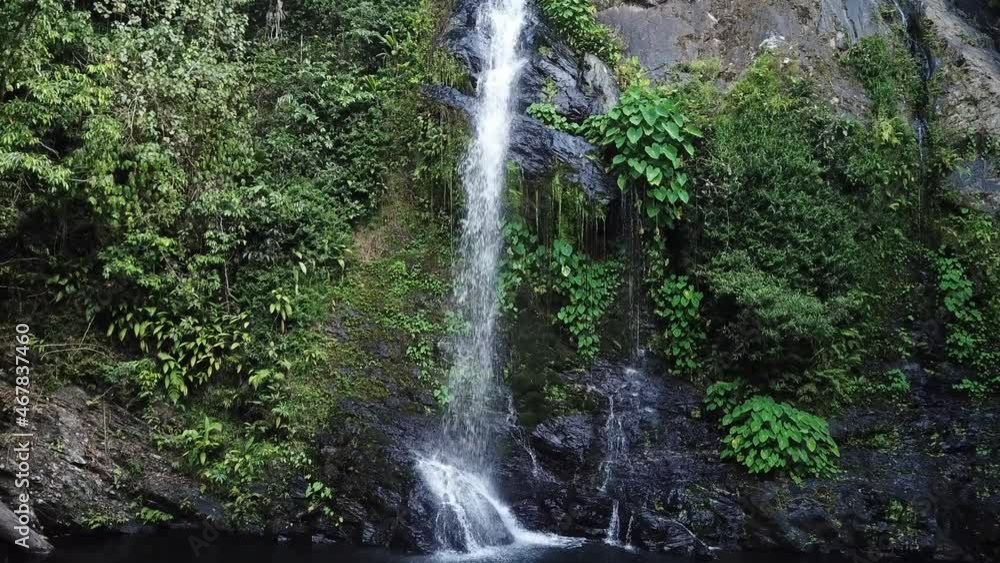 Drone aerial moving backwards a tropical green waterfall in rainforest Drone aerial moving backwards a tropical green waterfall in rainforest