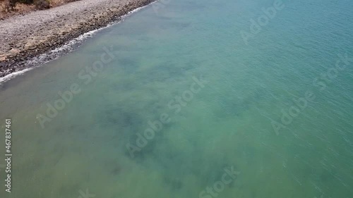 Drone flying low on water slow pan up over blue tropical beach water photo