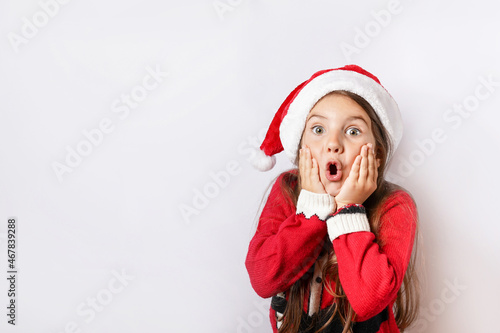 Christmas shocked and surprised child girl with red hat with head in hands on white background with copy space