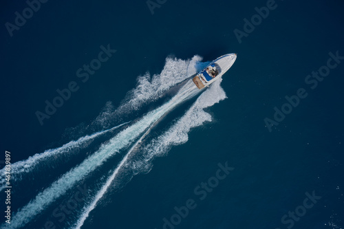 White speed boat fast movement on the water top view. Travel - image. Top view of a white high-speed boat. Diagonal boat movement on blue water top view.