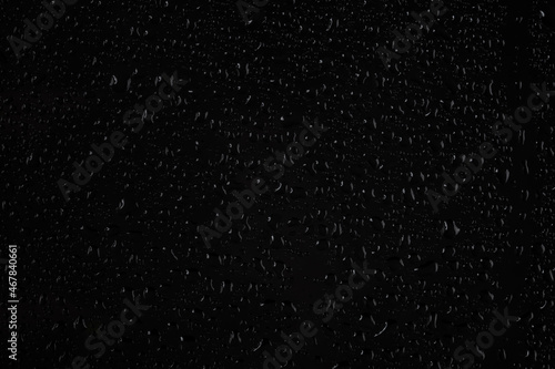 Water drops on glass on a black background.