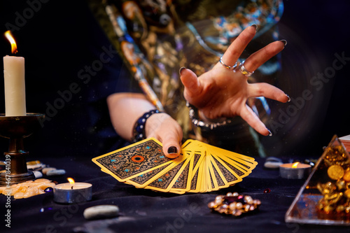 The fortune teller holds a fan of cards in her hands and casts a spell with her hand. Close-up. The concept of divination, magic and esotericism photo