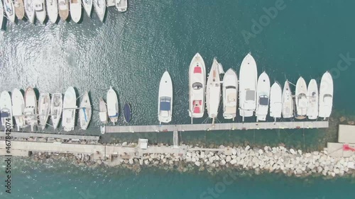 Aerial Drone Shot flying over a yacht port showing beautiful white yachts and boats in the port with the waves smoothly rocking the boats on the blue water photo