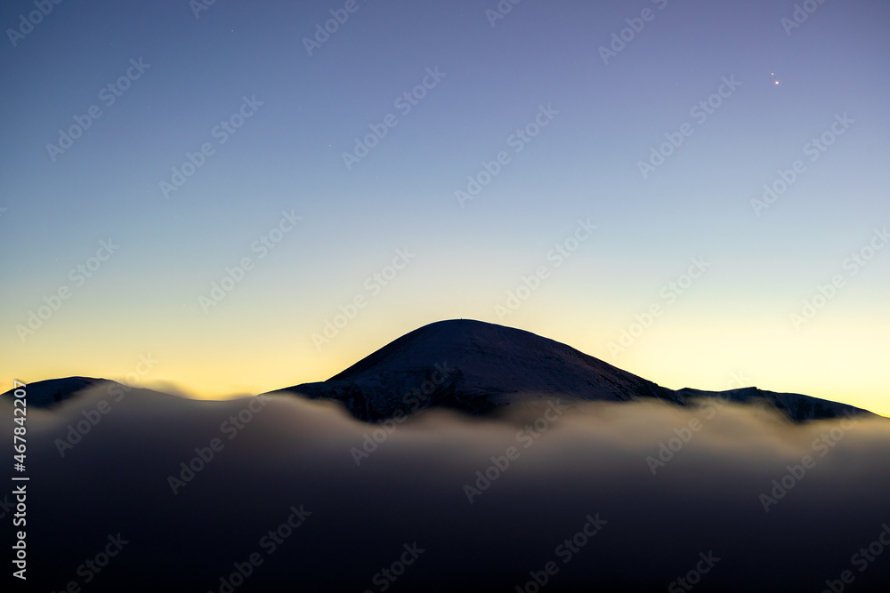 Beautiful mountain landscape with hazy peaks and foggy valley at sunset