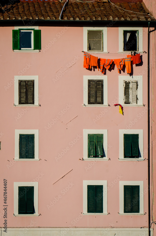 Vestiti da lavoro arancioni stesi ad asciugare fra le finestre di un palazzo di Livorno
