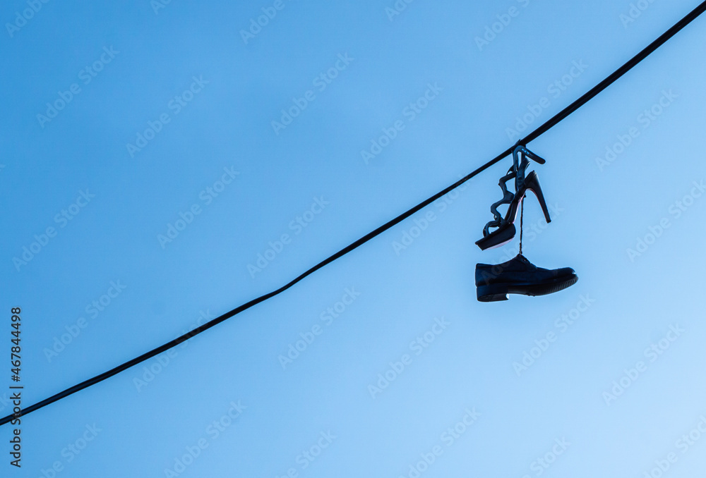 Mans and female classic shoes hanging on the electric wire against blue sky Mans and female classic shoes hanging on the electric wire against blue sky
