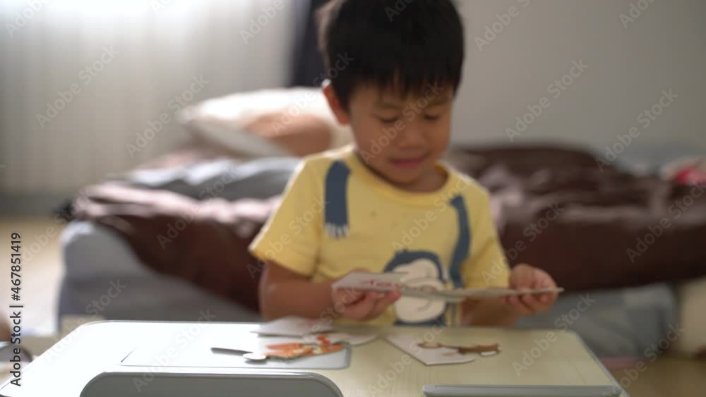 Asian boy about 4 years old building paper jigsaws with his mother at home Asian boy about 4 years old building paper jigsaws with his mother at home