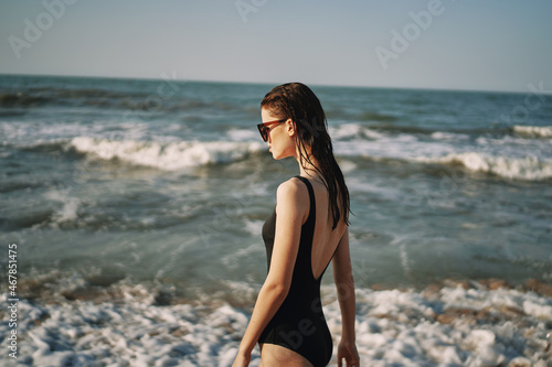 woman in black swimsuit walking on the beach ocean summer