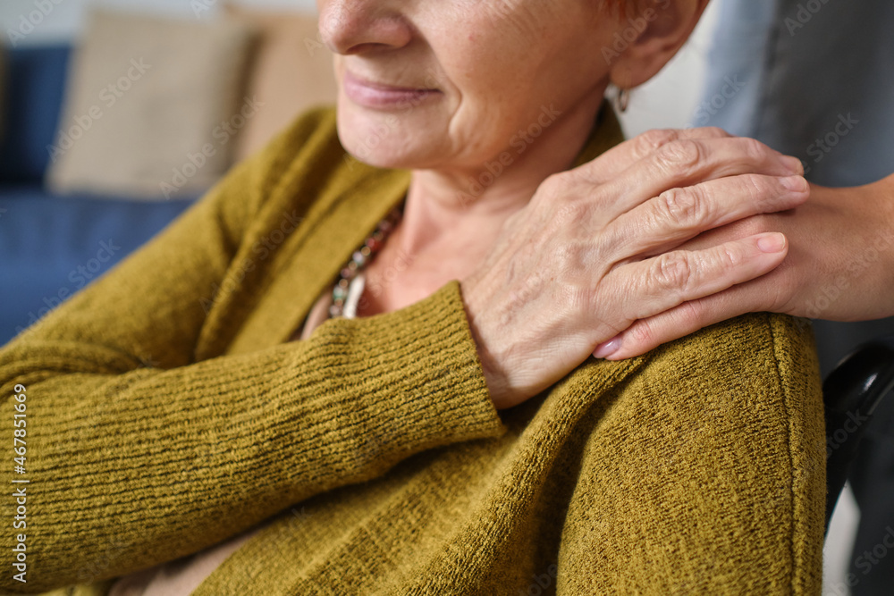 Close-up of senior woman holding hand of nurse while she taking her in a wheelchair Close-up of senior woman holding hand of nurse while she taking her in a wheelchair