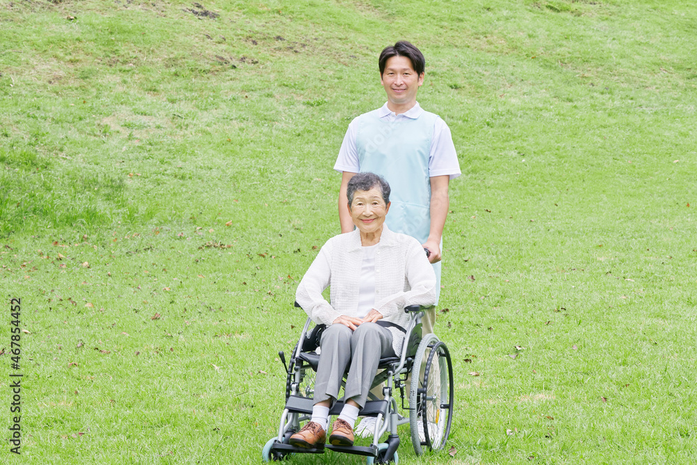 Obraz premium 介護士と車椅子に乗る高齢者 屋外