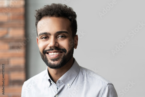 Fototapeta Naklejka Na Ścianę i Meble -  Young businessman closeup portrait, mixed race latin confident man smiling and looking to camera in modern office.