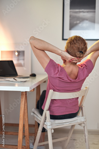 Woman working from home on a laptop and having pain in the neck.