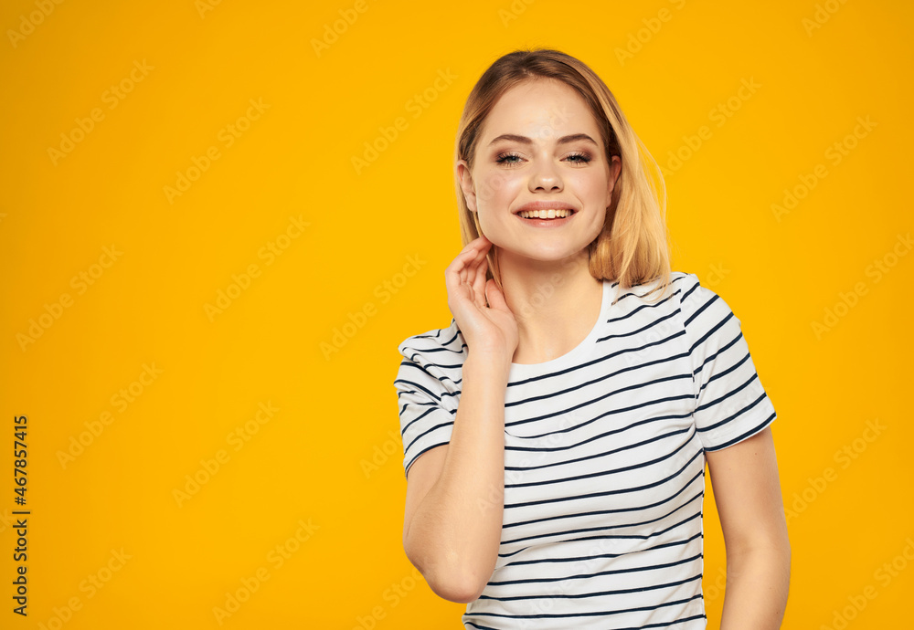 cheerful woman in a striped t-shirt gesturing with her hands yellow background cheerful woman in a striped t-shirt gesturing with her hands yellow background