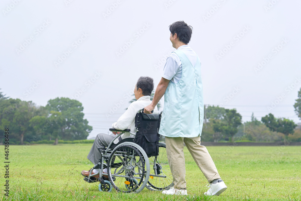 介護士と車椅子に乗る高齢者　屋外