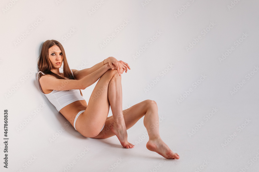 young beautiful girl, model appearance in white lingerie - bikini, in the studio on a white background