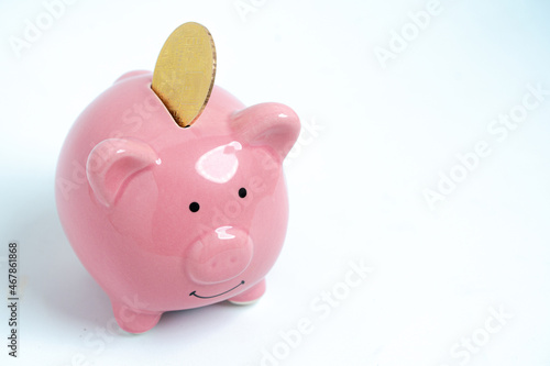 A happy Piggybank and bitcoin, with a white background, drop bitcoin in a piggybank.