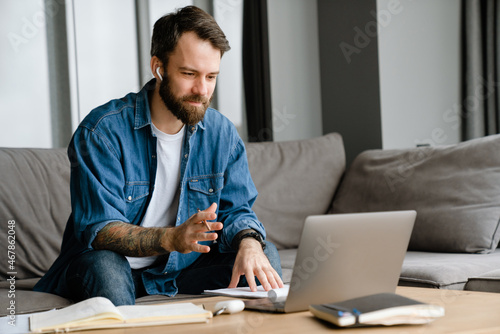 Bearded european man working with laptop while sitting on sofa