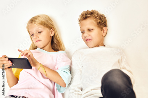 girl with a phone in her hands next to a boy playing games