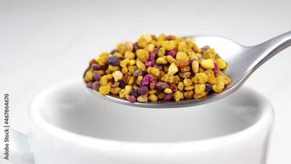 Pollen tea. Falling dry flower granules from a teaspoon into a white teacup in slow motion. Alternative medicine concept. Natural dietary supplement Pollen tea. Falling dry flower granules from a teaspoon into a white teacup in slow motion. Alternative medicine concept. Natural dietary supplement