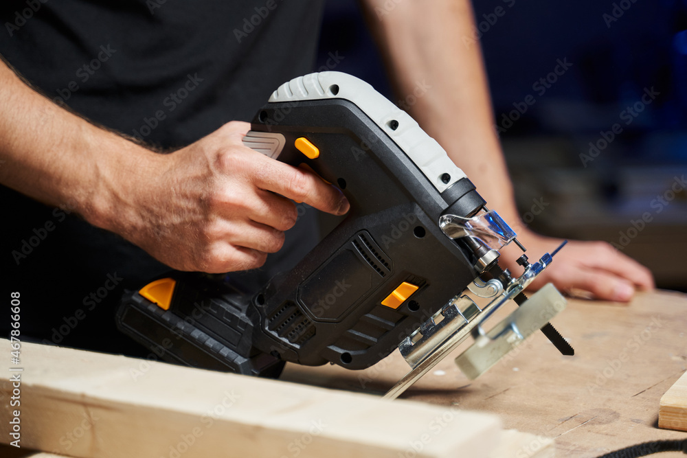 jigsaw with battery in men's hands jigsaw with battery in men's hands
