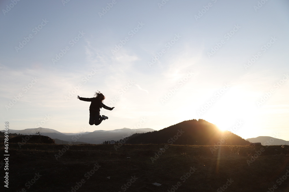 happy woman jumping into the air at sunset.