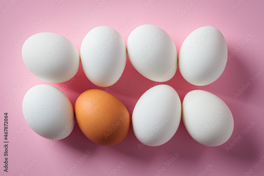White and brown raw chicken eggs on pink background. White and brown raw chicken eggs on pink background.