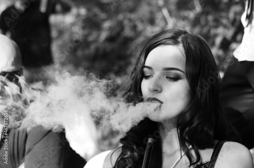 Sexy girl with smartphone smokes hookah