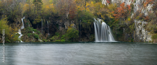 horizontal panorama view of calm lake with several waterfalls and colorful fall foliage photo