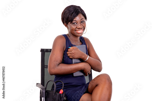 young businesswoman sitting on a chair holding a digital tablet against her chest smiling. photo