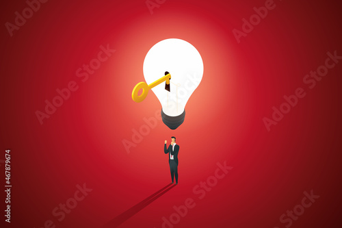 Businessman under light bulb with unlocked golden key.