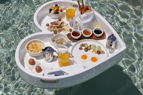 White heart shaped floating tray. Breakfast in pool in luxury resort. Top view. 